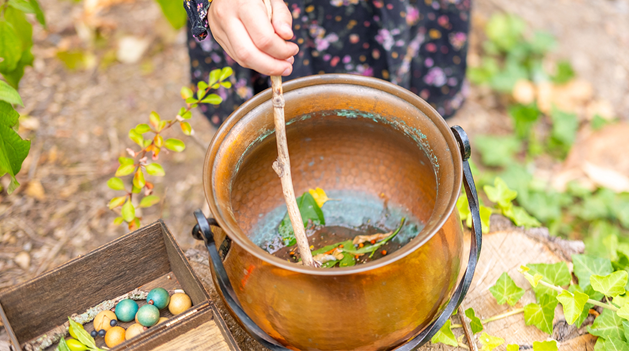 Child hand stirring copper cauldron with stick
