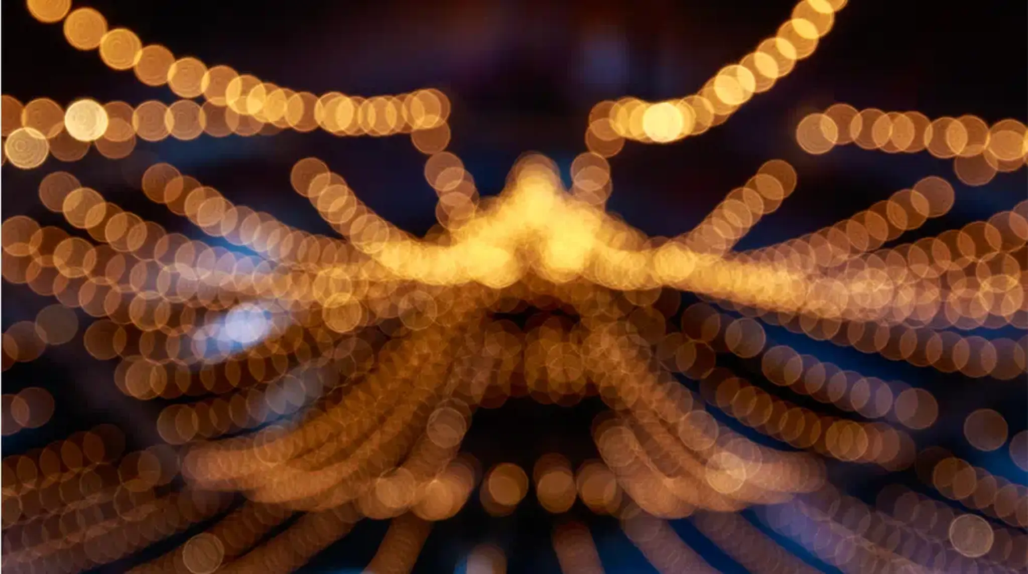 Blurred image of warm, glowing string lights against a dark background