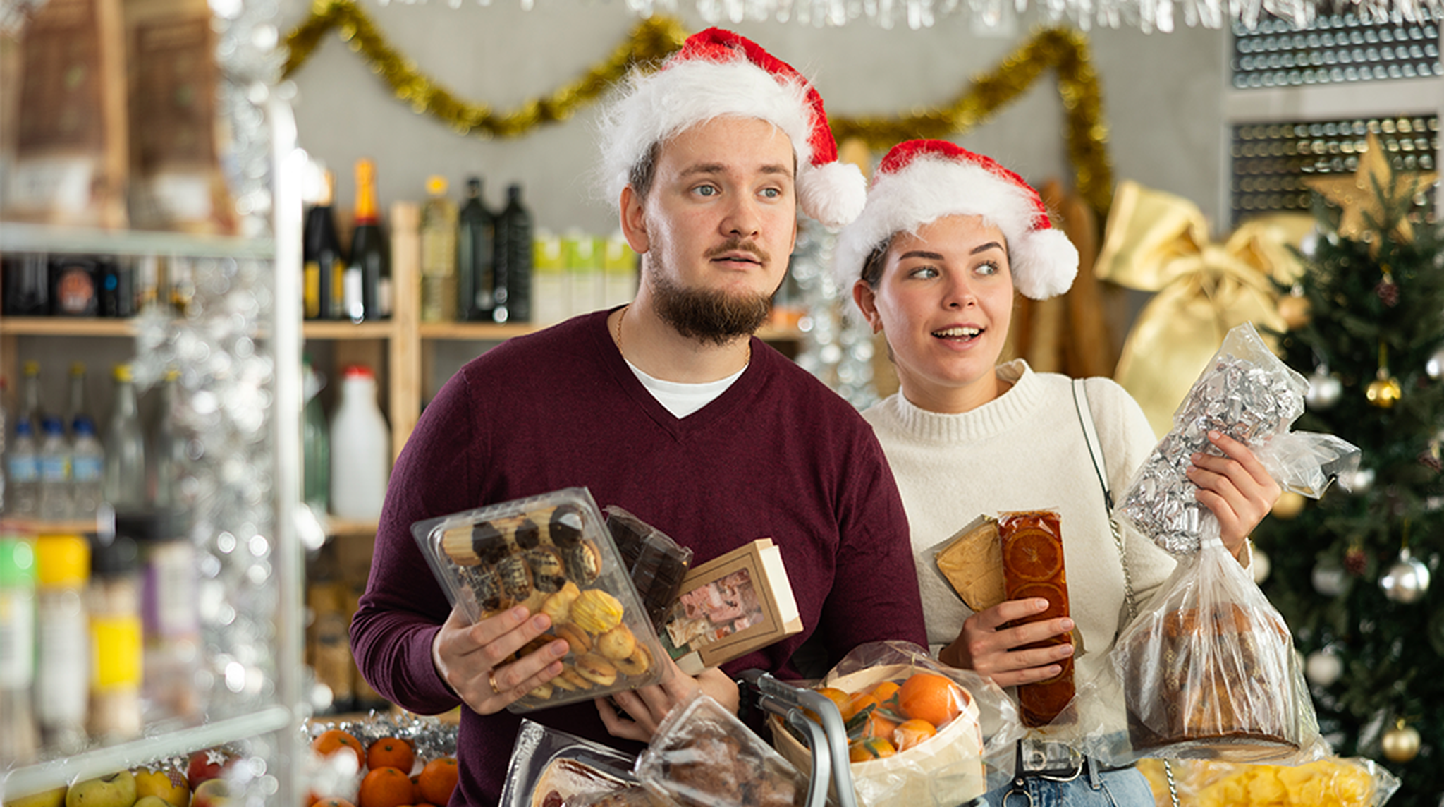 A couple in Santa hats shop for Christmas in a store