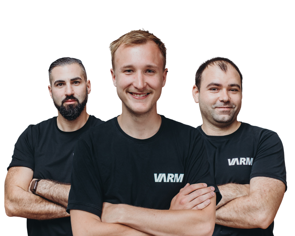 Drei VARM-Mitarbeiter im schwarzen VARM-T-Shirt stehen mit verschränkten Armen und blicken freundlich in die Kamera – Team für Einblasdämmung und Gebäudedämmung.