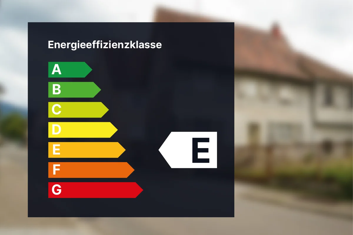Energieeffizienz-Bewertungstabelle mit den Kategorien A bis G, wobei Klasse E hervorgehoben ist. Unscharfer Hintergrund eines Wohngebäudes.