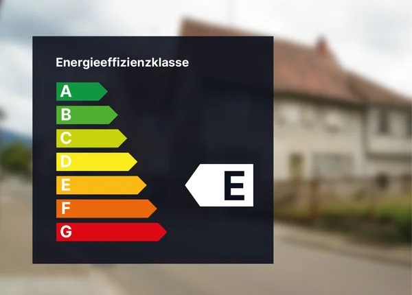Energieeffizienz-Bewertungstabelle mit den Kategorien A bis G, wobei Klasse E hervorgehoben ist. Unscharfer Hintergrund eines Wohngebäudes.