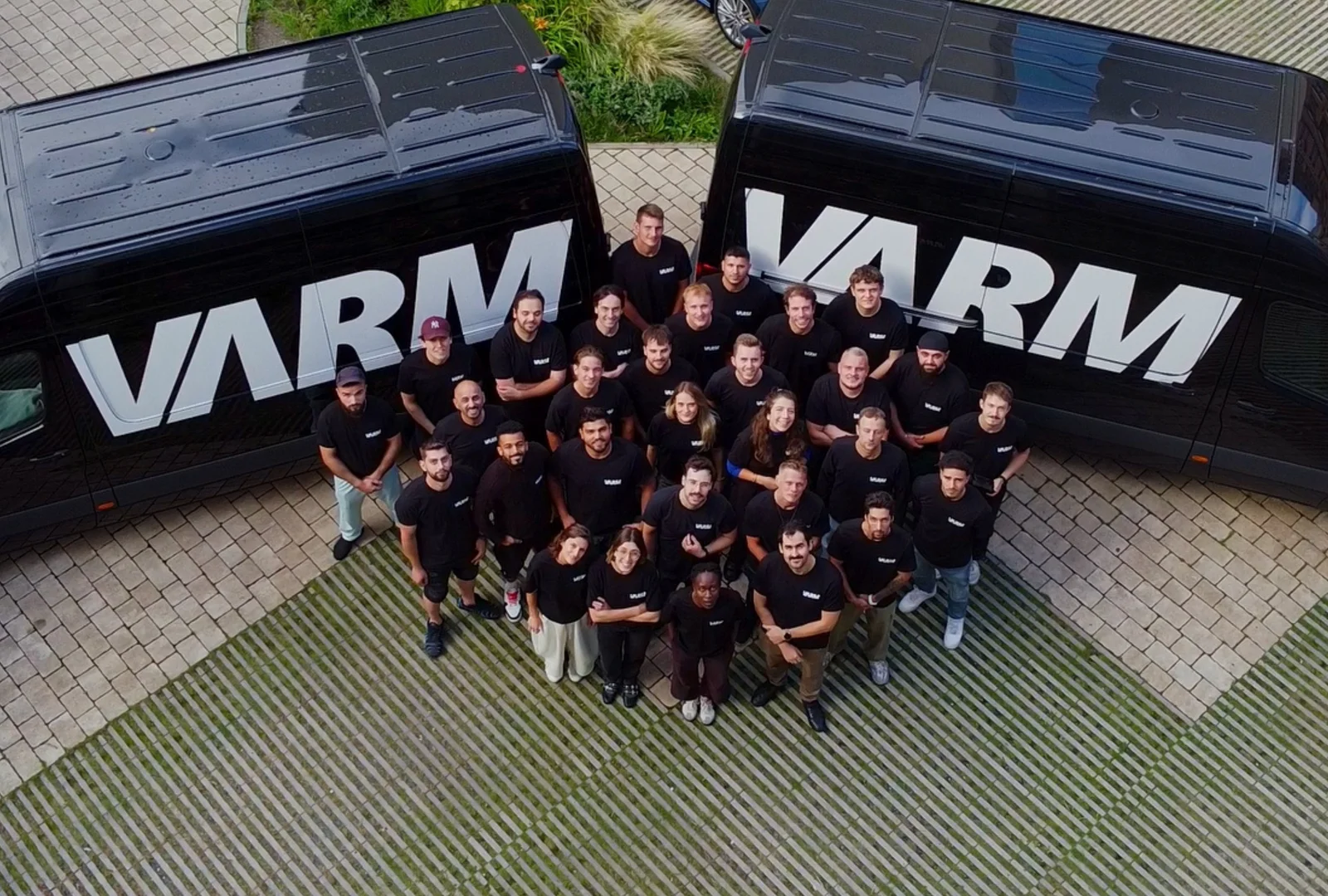 Gruppenfoto des VARM Teams zwischen zwei Firmenfahrzeugen mit VARM-Logo – Dämmprofis für Einblasdämmung und Gebäudedämmung in Deutschland.