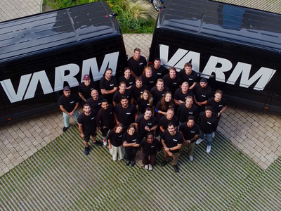 Gruppenfoto des VARM Teams zwischen zwei Firmenfahrzeugen mit VARM-Logo – Dämmprofis für Einblasdämmung und Gebäudedämmung in Deutschland.