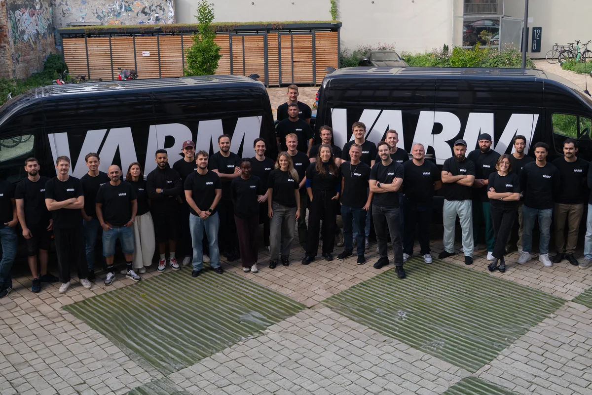 Team der VARM GmbH vor zwei Firmenfahrzeugen mit VARM-Logo. Gruppenfoto der Mitarbeiter am Standort Berlin, spezialisiert auf Einblasdämmung und Gebäudedämmung.