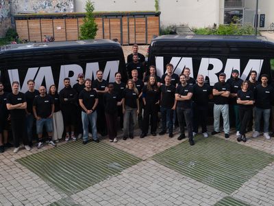 Team der VARM GmbH vor zwei Firmenfahrzeugen mit VARM-Logo. Gruppenfoto der Mitarbeiter am Standort Berlin, spezialisiert auf Einblasdämmung und Gebäudedämmung.