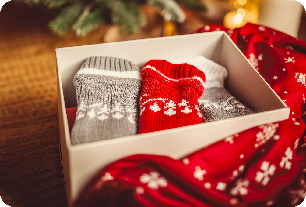 Vánoční dárková krabička s pletenými ponožkami u vánočního stromku