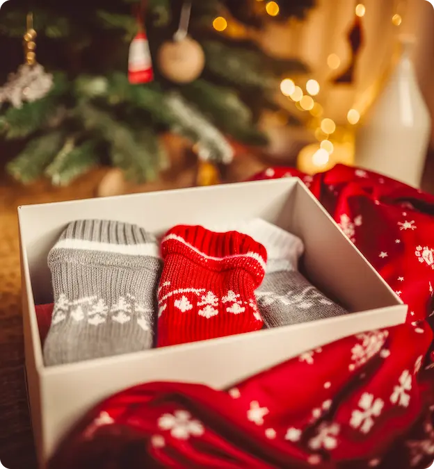 Vánoční dárková krabička s pletenými ponožkami u vánočního stromku