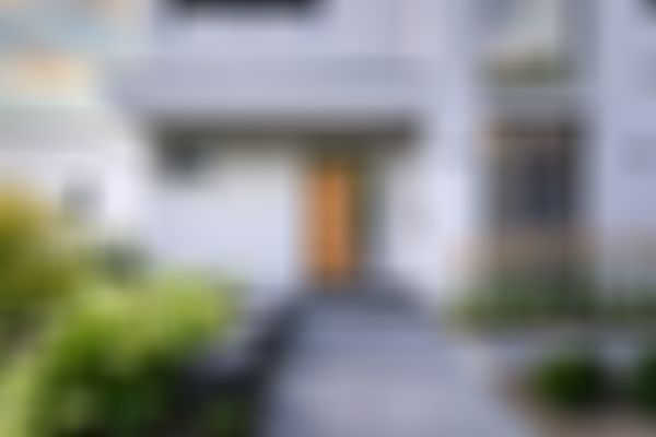 Das Bild zeigt einen überdachten Hauseingang mit großen Fliesen als Weg zur verhölzerten Haustüre.