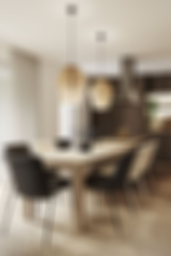 Moderner Essbereich mit Holztisch, unterschiedlichen Stühlen, Pendelleuchten und großen Fenstern. Küche im Hintergrund mit dunklen Holzschränken