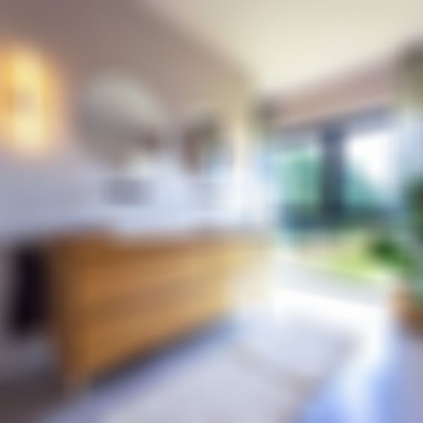 Modernes Badezimmer mit zwei Waschbecken auf einem Waschtisch aus Holz, runden Spiegeln und großen Fenstern mit Blick auf die grüne Landschaft.