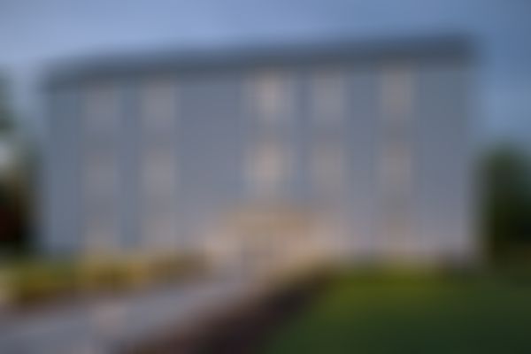 Modernes dreistöckiges Haus mit großen Fenstern, einem minimalistischen Garten und Wegbeleuchtung vor dem Hintergrund eines Abendhimmels.