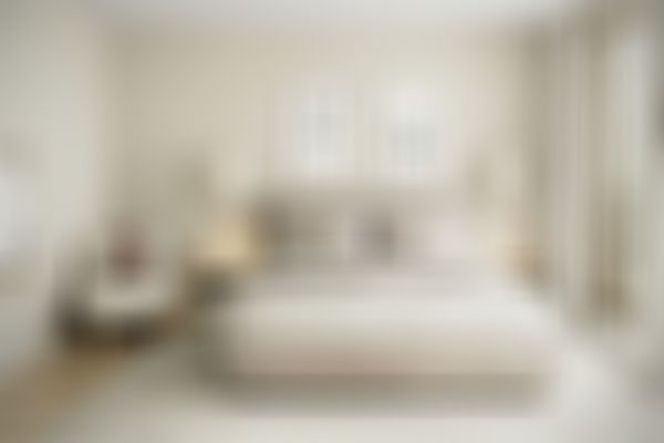 Gemütliches Kinderzimmer mit einem großen Bett, Beigetönen, Kunst an den Wänden, Pendelleuchten, einem Plüschsessel mit einem Känguru-Stofftier und einem großen Fenster.