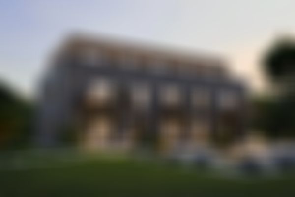 Modernes zweistöckiges Gebäude in der Abenddämmerung mit Balkonen, großen Fenstern und einem angelegten Garten mit Sitzgelegenheiten im Freien und stimmungsvoller Beleuchtung.