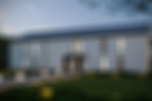 Mehrfamilienhaus mit großen Fenstern, einem von leuchtenden Kugellampen gesäumten Weg, umgeben von einem gepflegten Rasen und Bäumen in der Abenddämmerung.