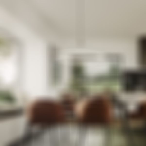 Moderner Essbereich mit rundem Tisch, vier orangefarbenen Stühlen und einer runden Deckenleuchte. Großes Fenster mit Sitzbank, grünen Kissen und Blick nach draußen.