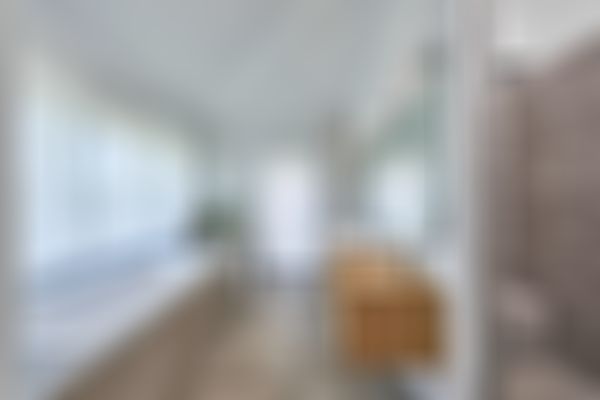 Das Bild zeigt ein luxuriöses Badezimmer mit eingebauter Badewanne und einer begehbaren Dusche mit einer Sitzmöglichkeit.