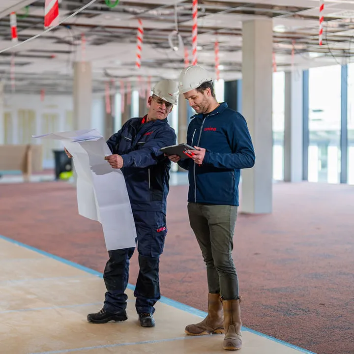 Overleg binnen met bouwtekening kijkend op tablet Avans Hogeschool