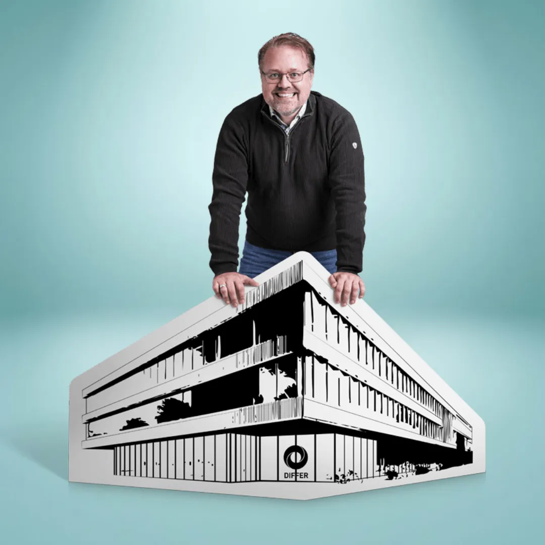 Man smiling, leaning on a large monochrome illustration of a modern building labeled "DIFER" against a light blue background.
