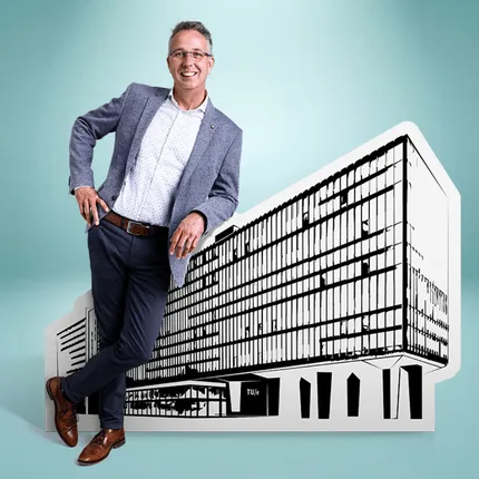 Man in a blazer leans on a large monochrome cutout of a modern building against a turquoise background.