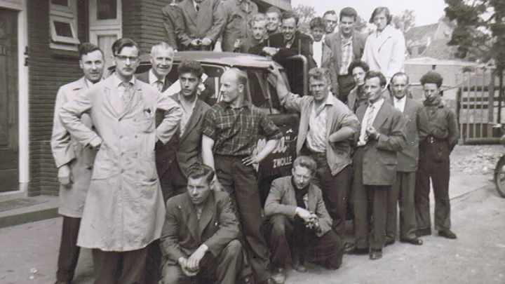 Historische foto uit1956 met twintig mannen die om de eerste Tempo vrachtwagen van Unica aan de Brink in Zwolle staan