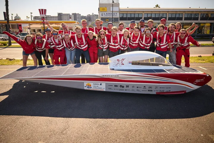 Team van Solar Team Twente allemaal gehuld in rode kleding voor hun zonnewagen