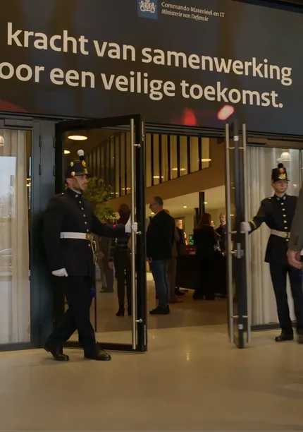 De entree van het IT-leveranciers evenement 2025, waarbij mannen in een ouderwets politiepak de deur openen voor een gast.