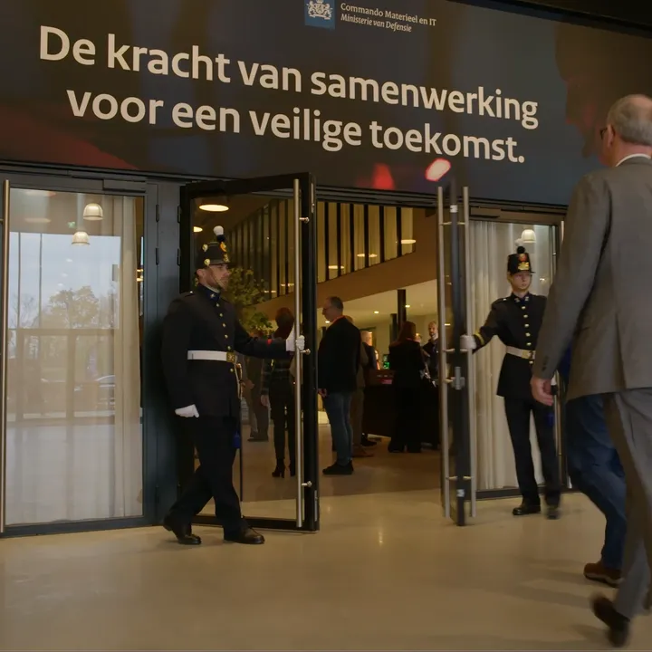 De entree van het IT-leveranciers evenement 2025, waarbij mannen in een ouderwets politiepak de deur openen voor een gast.