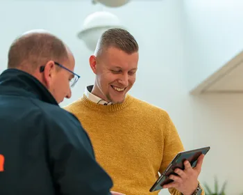 Twee medewerkers van Unica in gesprek; één in Unica-jas en één in okergele trui bekijkt lachend een tablet.  Deze tekst is kort, beschrijvend en geschikt voor gebruik op een website (inclusief de nieuwe corporate site). Laat me weten als je een alternatieve insteek wilt, zoals formeler of met focus op technologie.