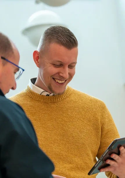 Twee medewerkers van Unica in gesprek; één in Unica-jas en één in okergele trui bekijkt lachend een tablet.  Deze tekst is kort, beschrijvend en geschikt voor gebruik op een website (inclusief de nieuwe corporate site). Laat me weten als je een alternatieve insteek wilt, zoals formeler of met focus op technologie.