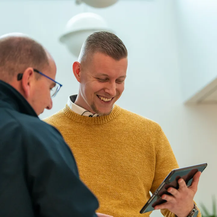 Twee medewerkers van Unica in gesprek; één in Unica-jas en één in okergele trui bekijkt lachend een tablet.  Deze tekst is kort, beschrijvend en geschikt voor gebruik op een website (inclusief de nieuwe corporate site). Laat me weten als je een alternatieve insteek wilt, zoals formeler of met focus op technologie.