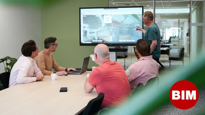 Bim coordinators in overleg en iets aanwijzend op grote scherm met bim stip