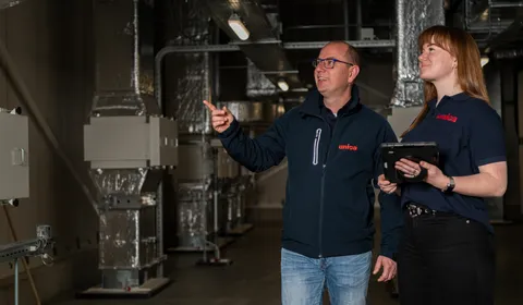 "Twee medewerkers van Unica Watertechniek inspecteren een technische ruimte met HVAC-installaties, gericht op efficiënte en veilige wateroplossingen."