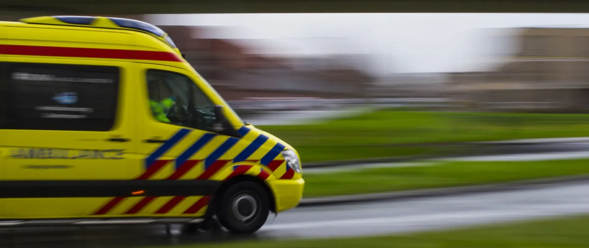Beeld van ambulance die onder viaduct rijdt