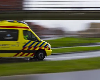 Beeld van ambulance die onder viaduct rijdt