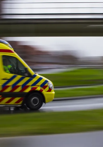 Beeld van ambulance die onder viaduct rijdt