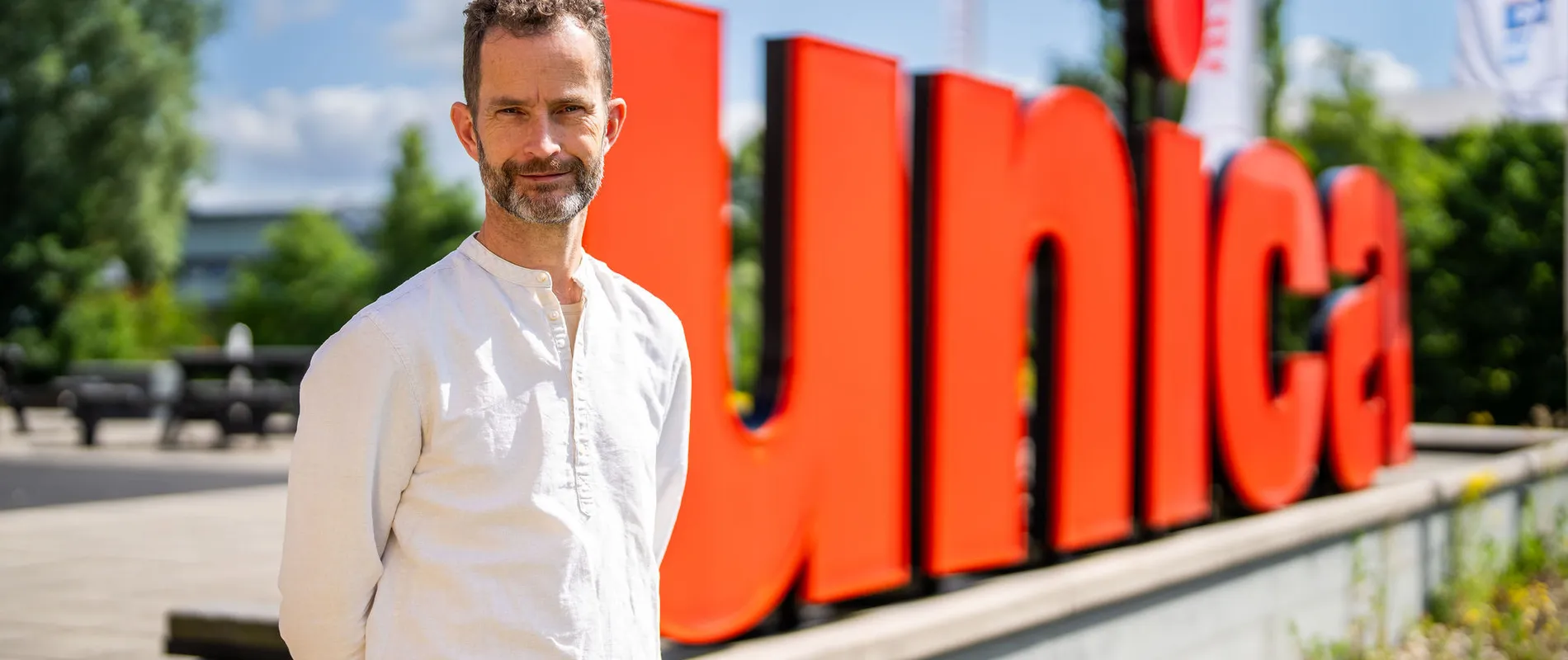 Hans den Otter staat voor grote rode Unica letters