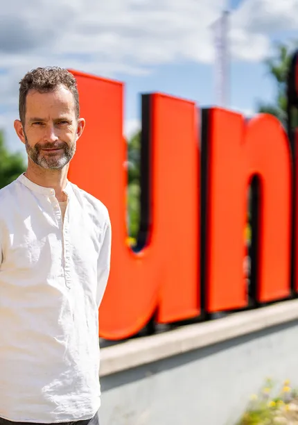Hans den Otter staat voor grote rode Unica letters