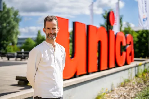Hans den Otter staat voor grote rode Unica letters