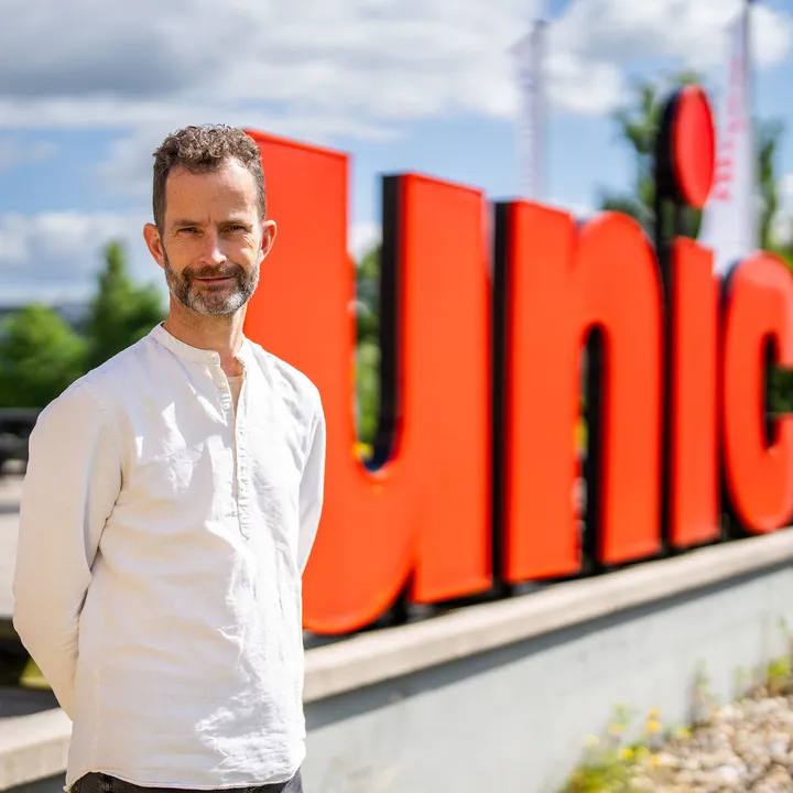 Hans den Otter staat voor grote rode Unica letters