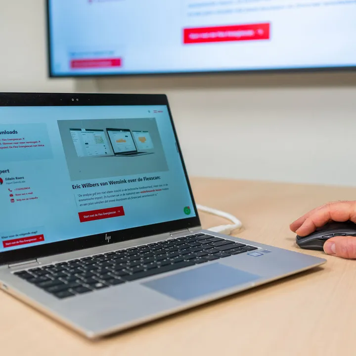 Website van Flexscan met advies over energieverbruik, subsidies (UBS) en consultancy (UES) op laptop in bespreking.