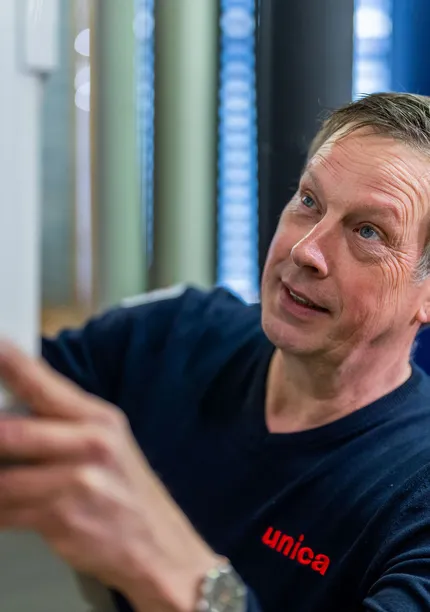 Unica-monteur voert handmatige controle uit op installatiepaneel tijdens onderhoudsronde.