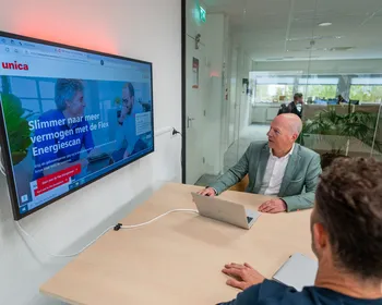 Collega’s in overleg terwijl de Flex Energiescan zichtbaar is op het scherm in een vergaderruimte.