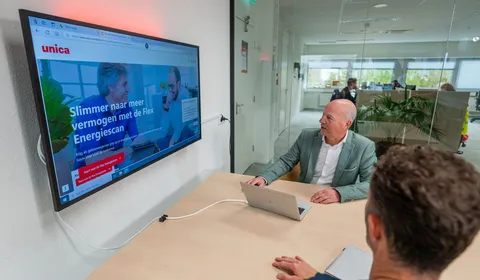 Collega’s in overleg terwijl de Flex Energiescan zichtbaar is op het scherm in een vergaderruimte.