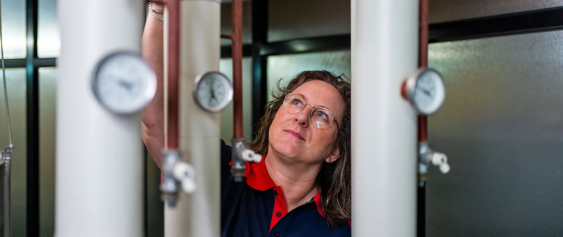 Unica-technicus inspecteert leidingen en meters in installatieruimte met focus op regelgeving.