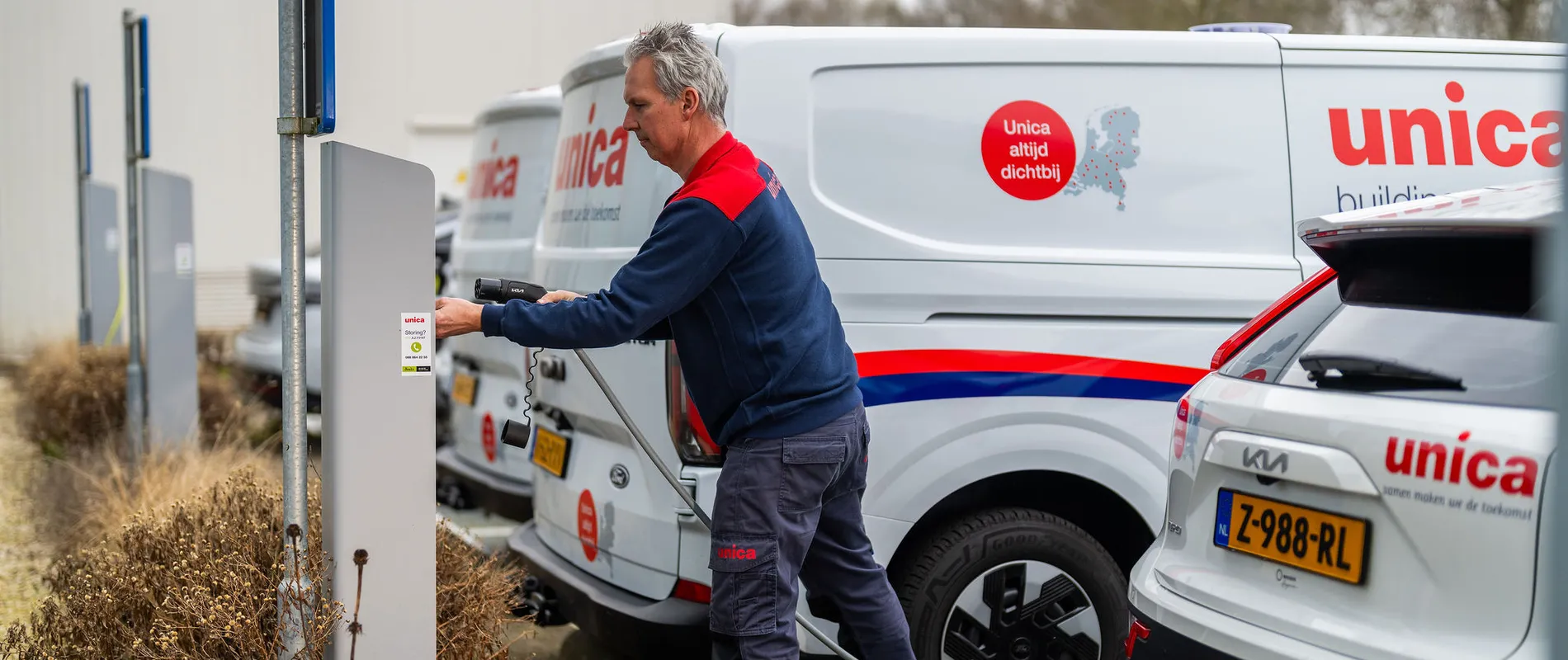Monteur van Unica sluit elektrische bedrijfswagen aan op laadpaal, onderdeel van e-mobility strategie.