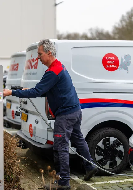 Monteur van Unica sluit elektrische bedrijfswagen aan op laadpaal, onderdeel van e-mobility strategie.