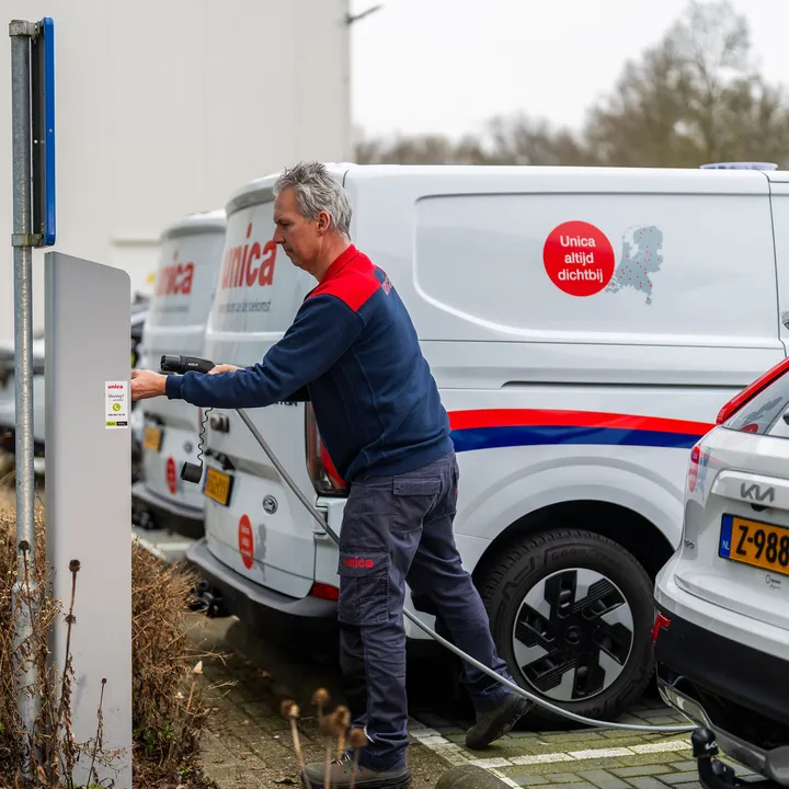 Monteur van Unica sluit elektrische bedrijfswagen aan op laadpaal, onderdeel van e-mobility strategie.