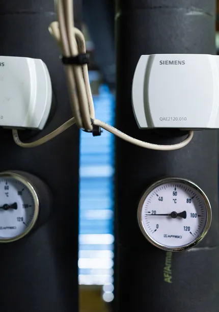 Detailopname van temperatuurmeters en sensoren in technische ruimte van een installatie.