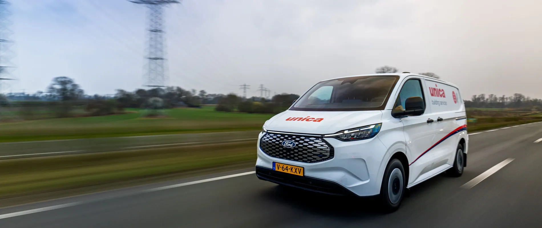 Unica bus rijdt over de snelweg door een landelijk landschap.
